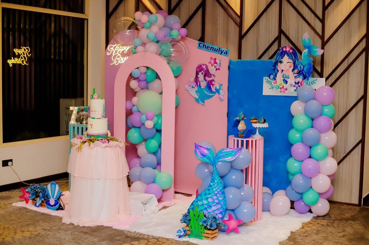 A children's birthday set-up with balloons, a cake and a mermaid theme