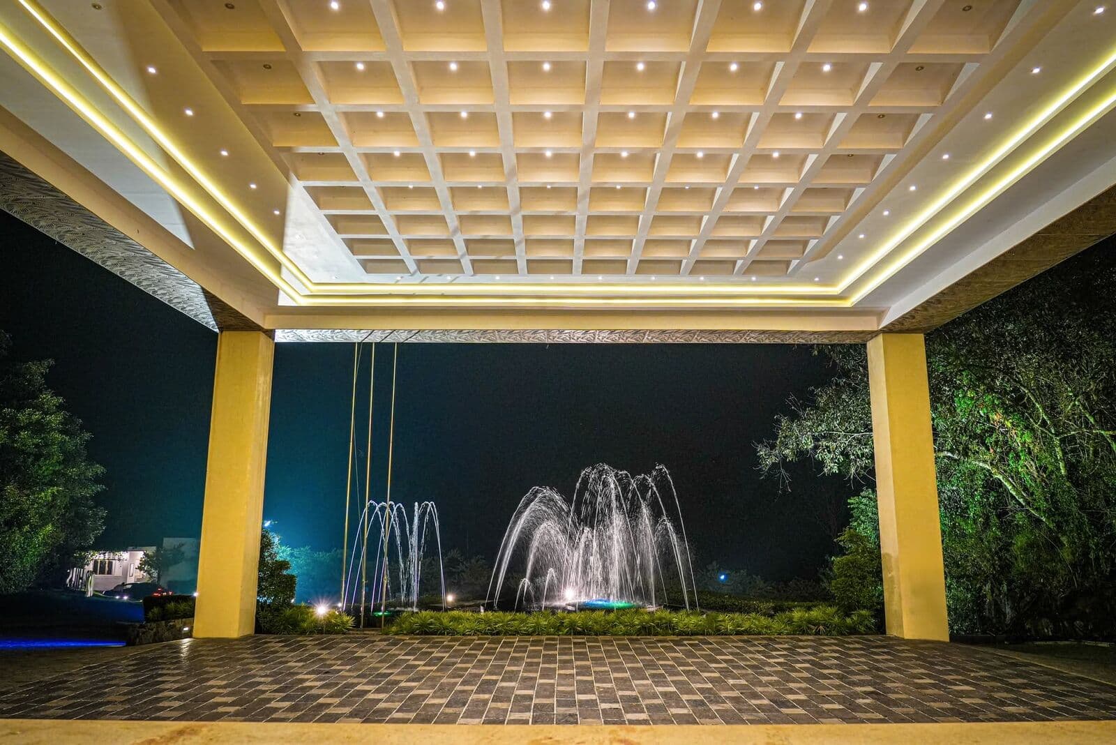 The entrance at night, looking out at the lit fountains