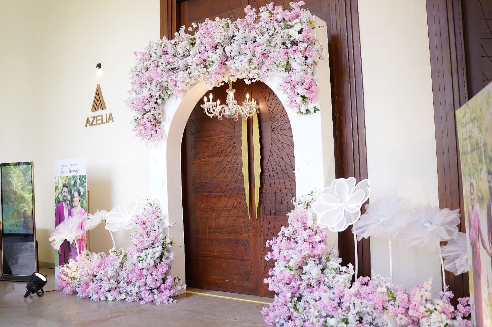 The Azelia hall's arched wooden doors framed by pink and white flowers