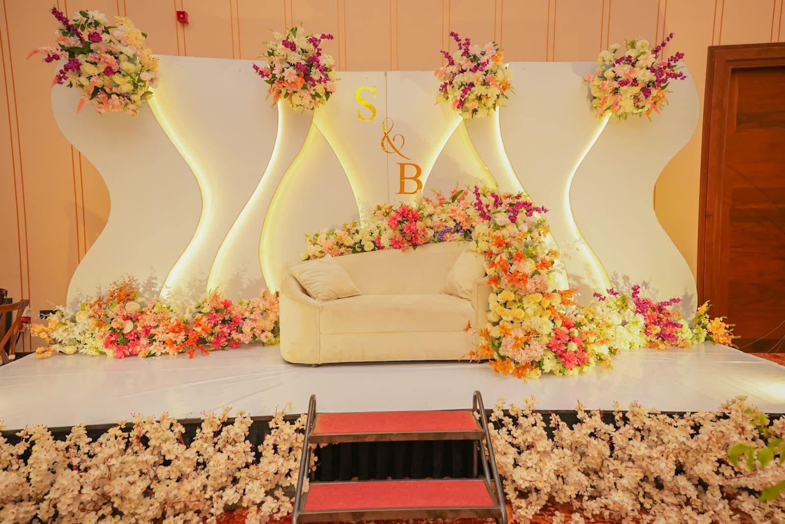 The Camelia hall's stage set with a cream sofa, flowers and red steps