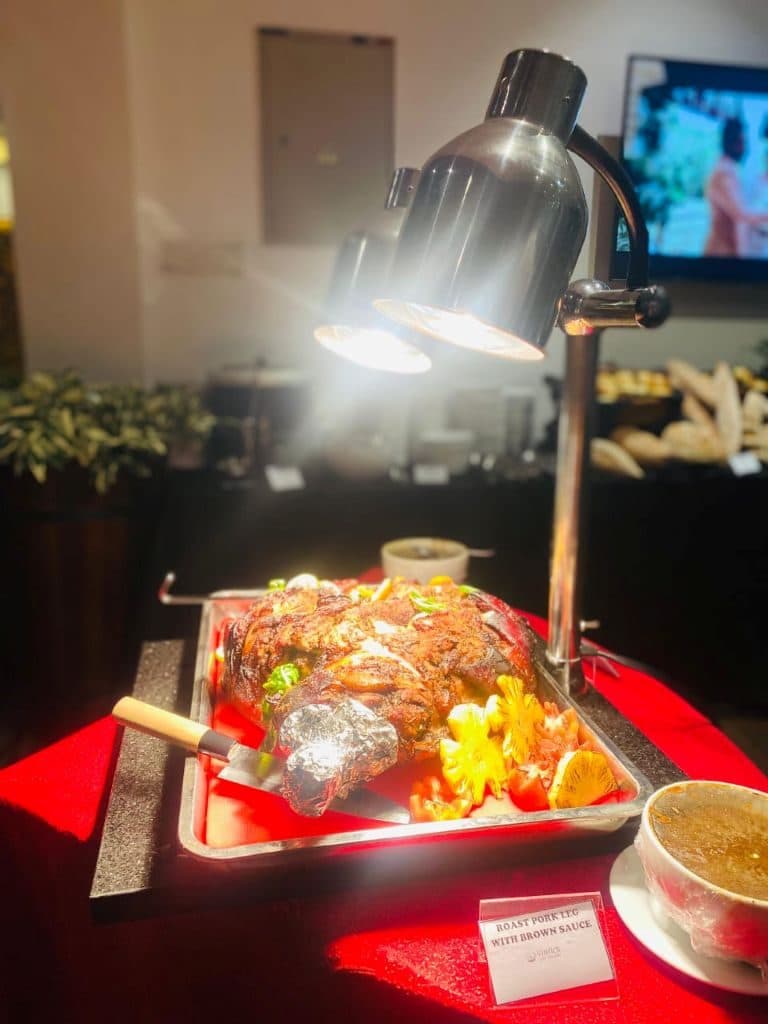 A roast under a warming lamp on a red-covered buffet table