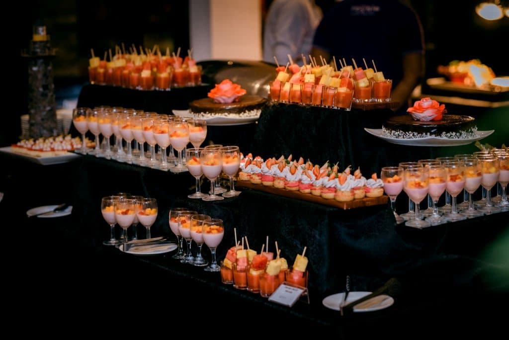Rows of dessert cups and canapés on a dark display table