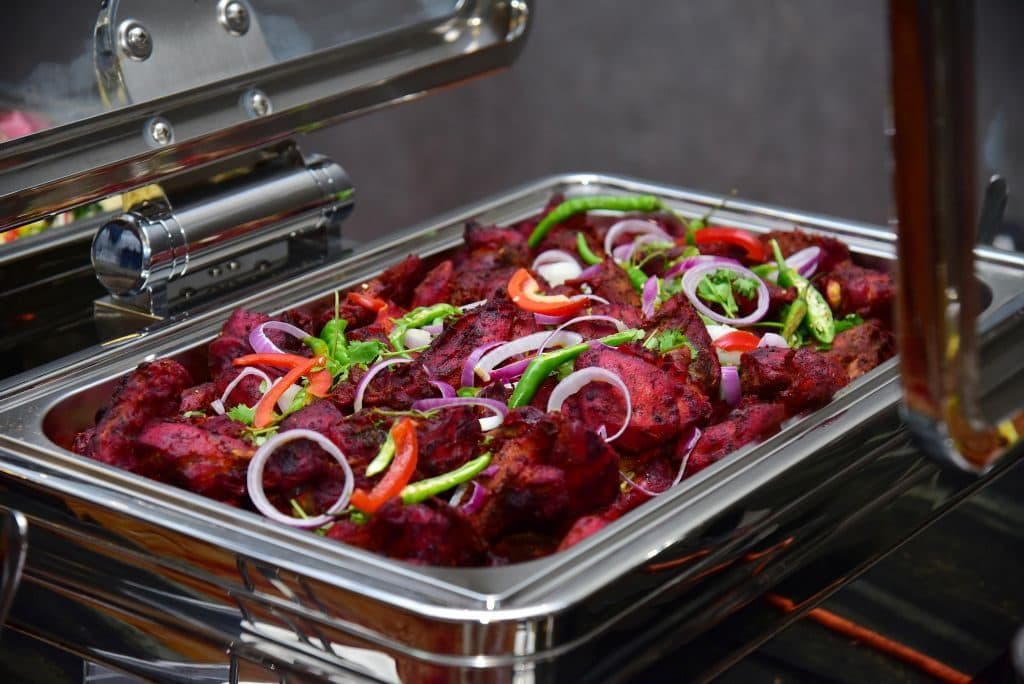 A chafing dish of red chilli beef with peppers and onion