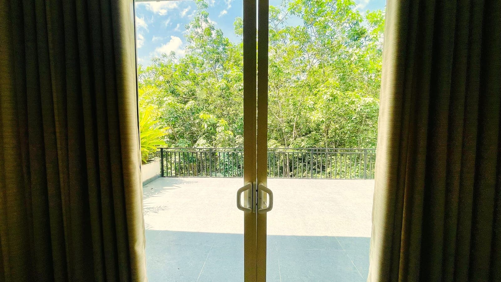 A balcony door looking out onto green trees