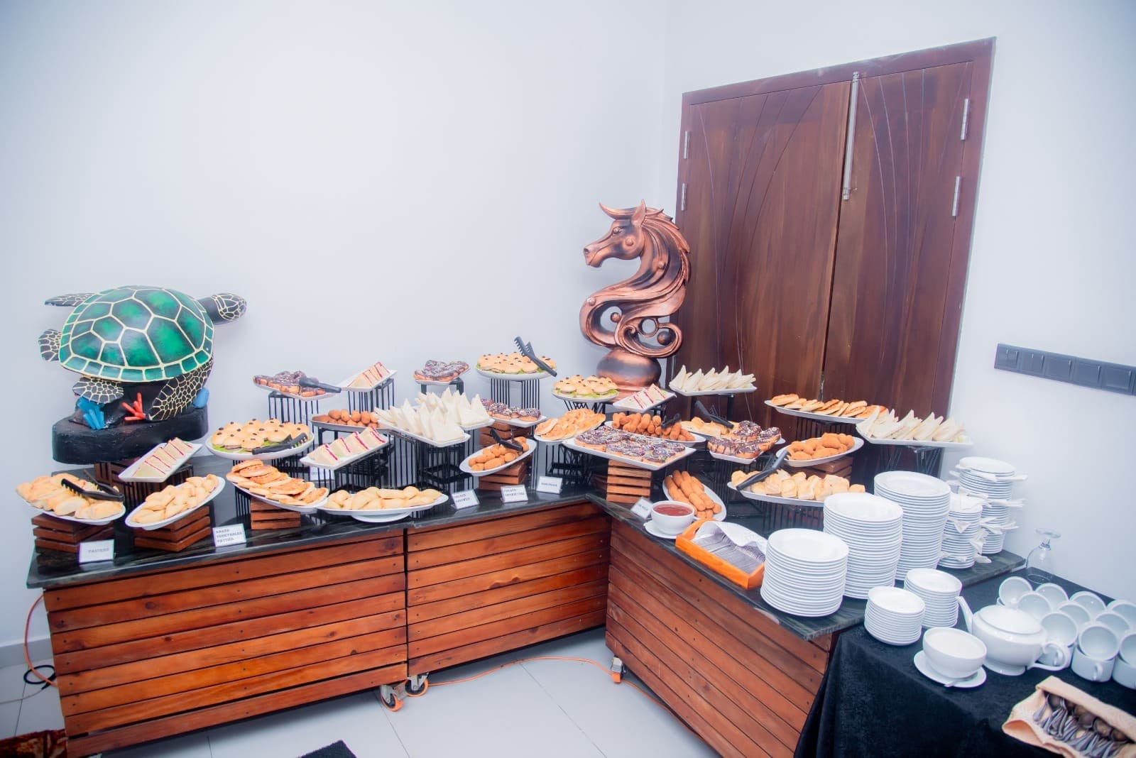 A wooden buffet counter with plates and serving dishes in a bright hall