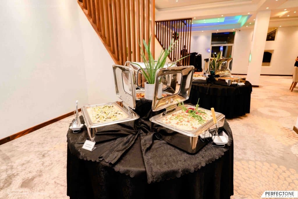 Silver serving dishes on a round table set for the weekend buffet