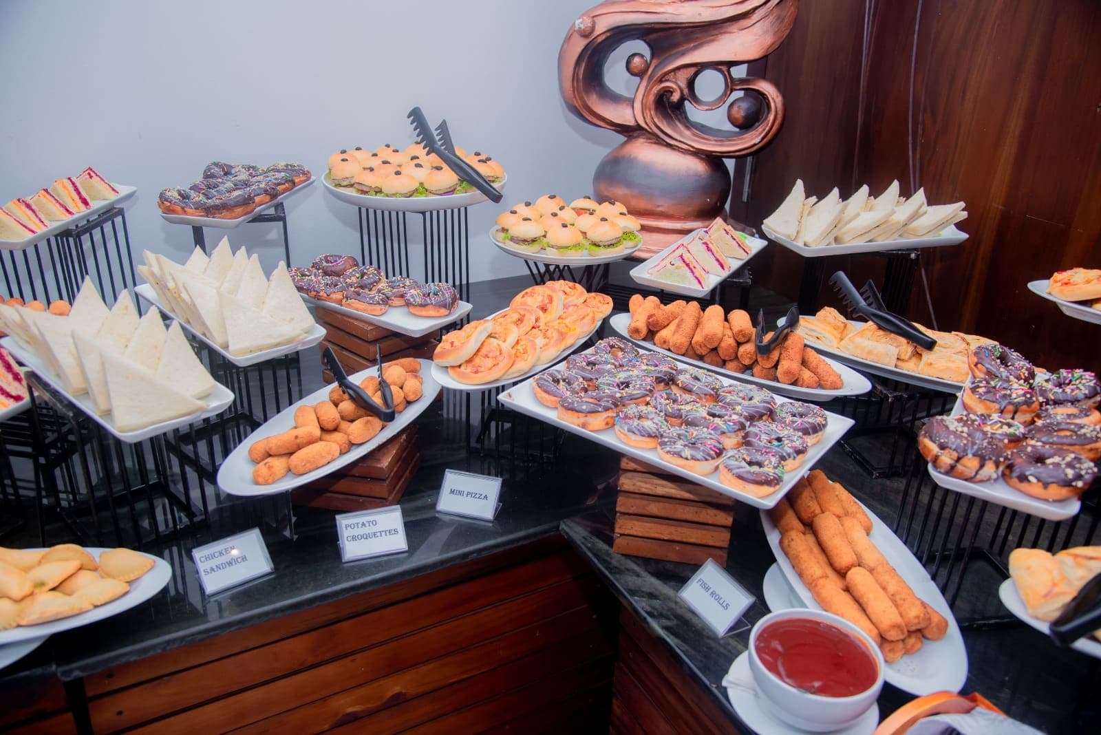 A buffet counter laid with pastries, sandwiches and sweets