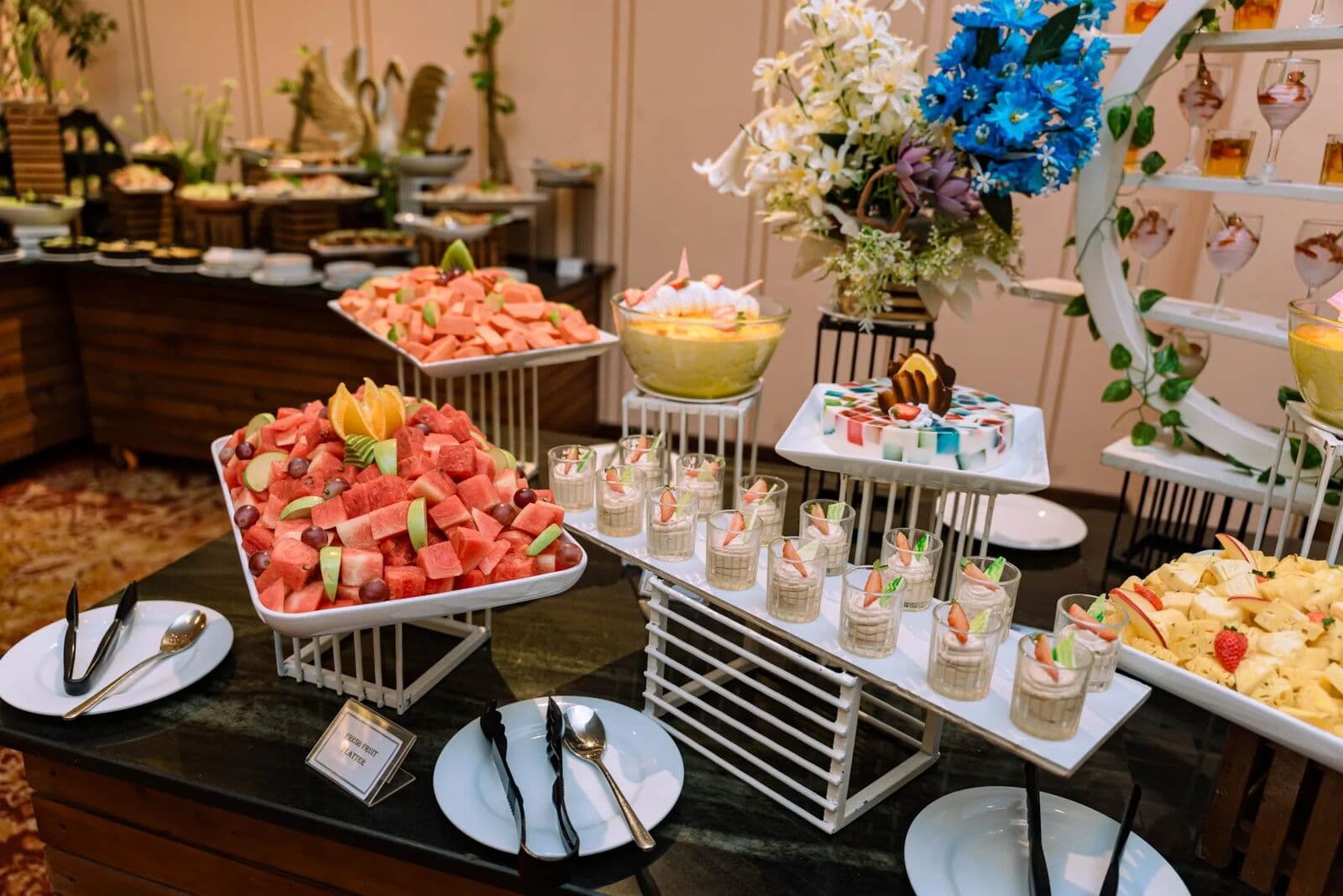 Trays of watermelon and mixed fruit with rows of dessert cups