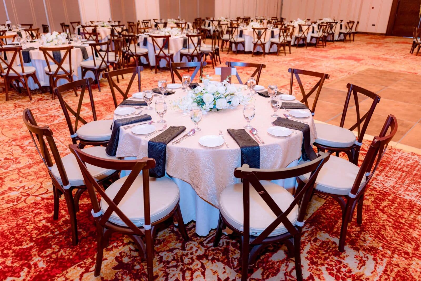 A round table with white linen, navy napkins and wooden chairs