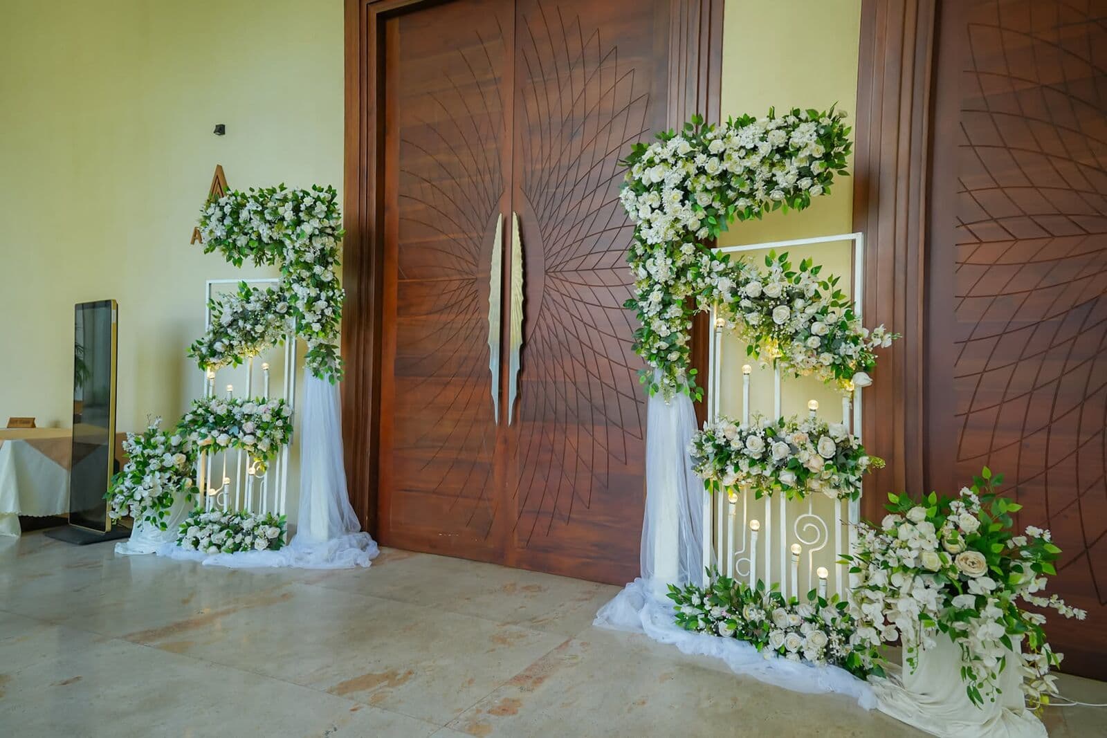 Tall wooden hall doors framed with white flowers and greenery