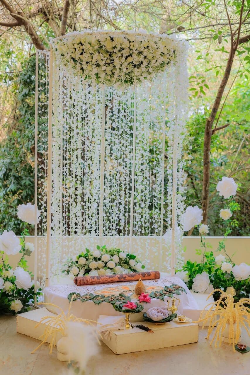 A poruwa under a hanging ring of white flowers in the garden