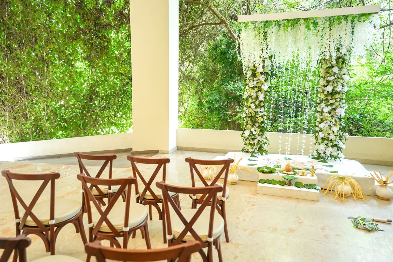 Chairs set out on the terrace facing a poruwa framed by greenery