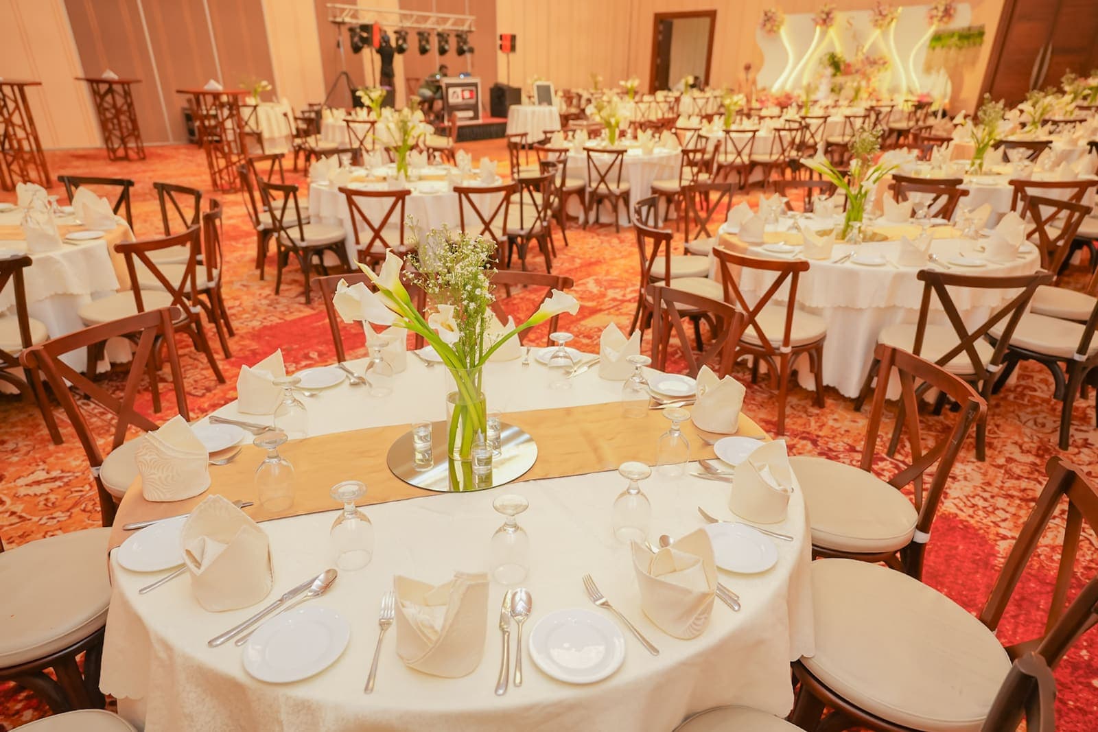 Round tables with white linen and flower centrepieces in a hall
