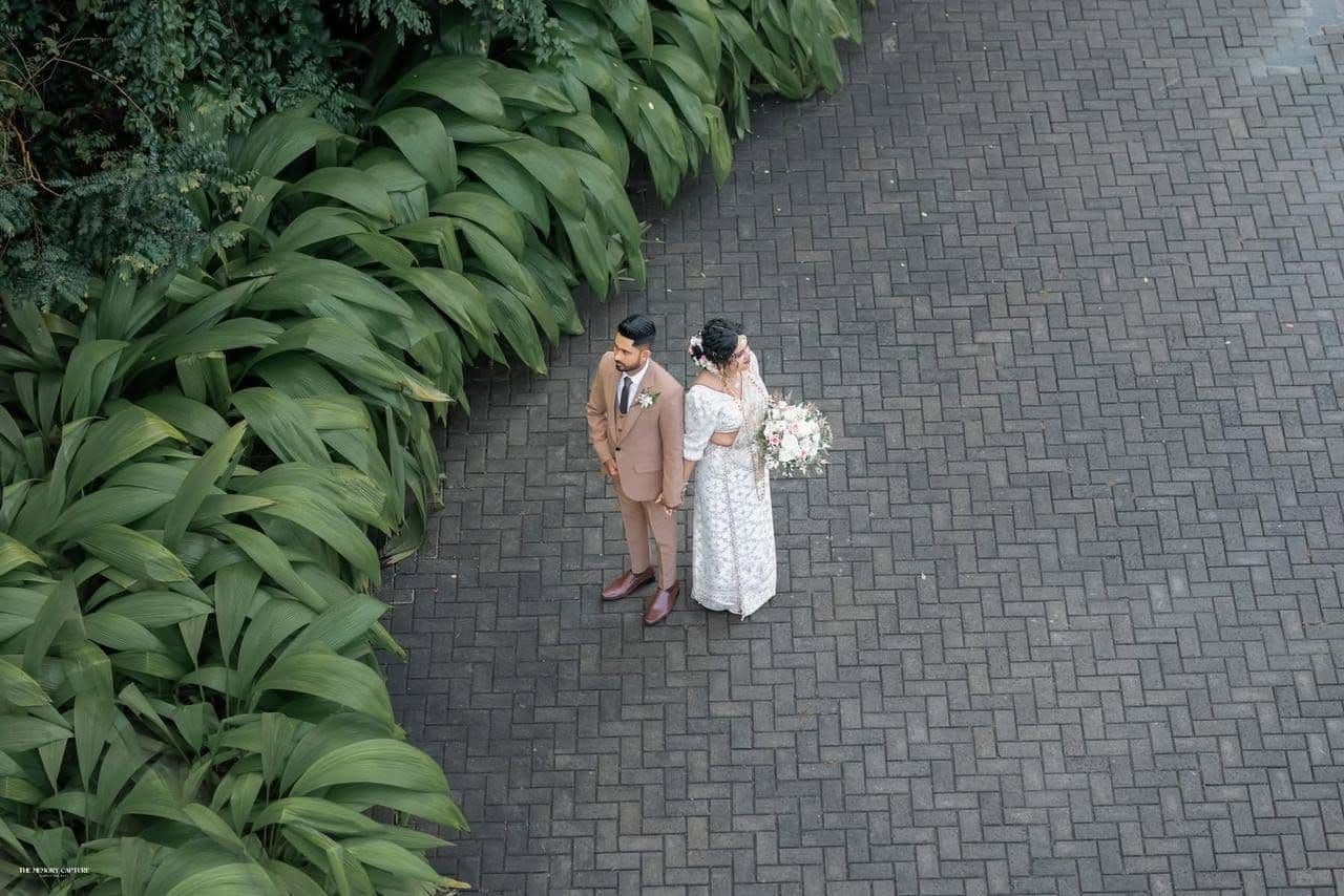 A couple seen from above on the curved stone paving between lawns and hedges