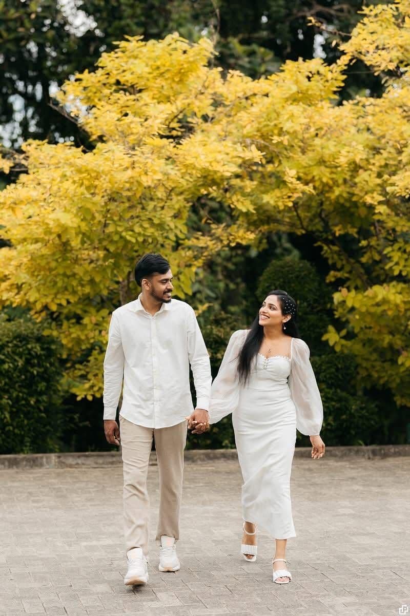 A couple's pre-shoot, walking under a tree with bright yellow leaves